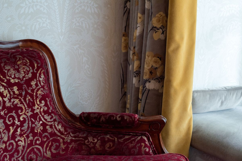 An antique red velvet and polished wood chair against patterned wallpaper at rockhill house estate letterkenny county donegal hotel
